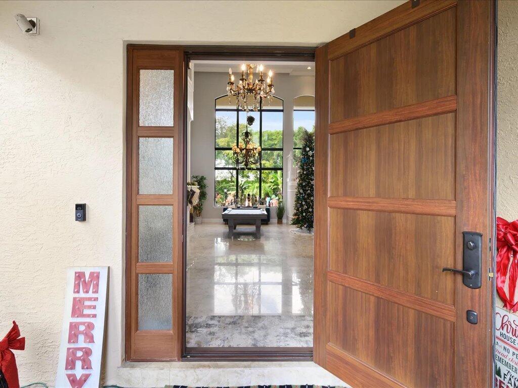 A view through an open wooden front door into a foyer with a pool table — 10596 Versailles Boulevard, Wellington FL 33449, WELLINGTON, FL