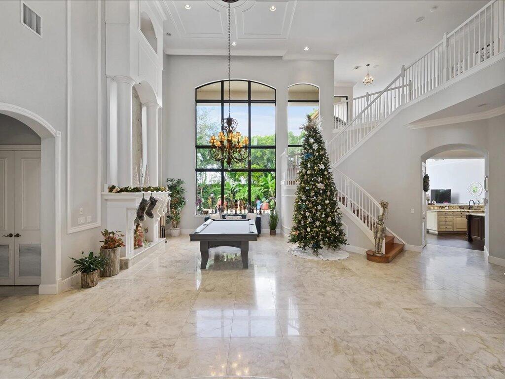 A spacious foyer with marble floors, a pool table, a large Christmas tree, and staircase — 10596 Versailles Boulevard, Wellington FL 33449, WELLINGTON, FL