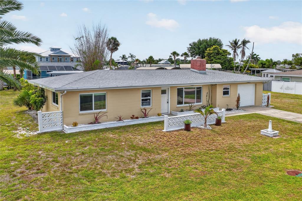 A single-story tan house with a brick chimney and a white decorative concrete block wall — 1447 LEMON BAY DRIVE, ENGLEWOOD, FL