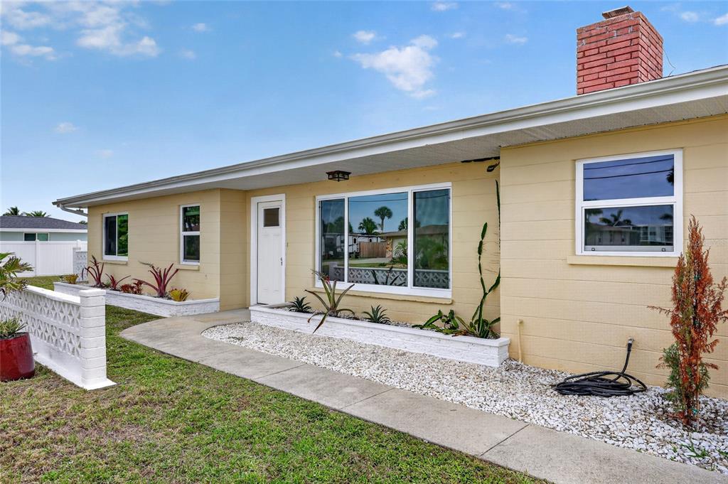 A single-story house with yellow siding, a brick chimney, and a white concrete walkway — 1447 LEMON BAY DRIVE, ENGLEWOOD, FL