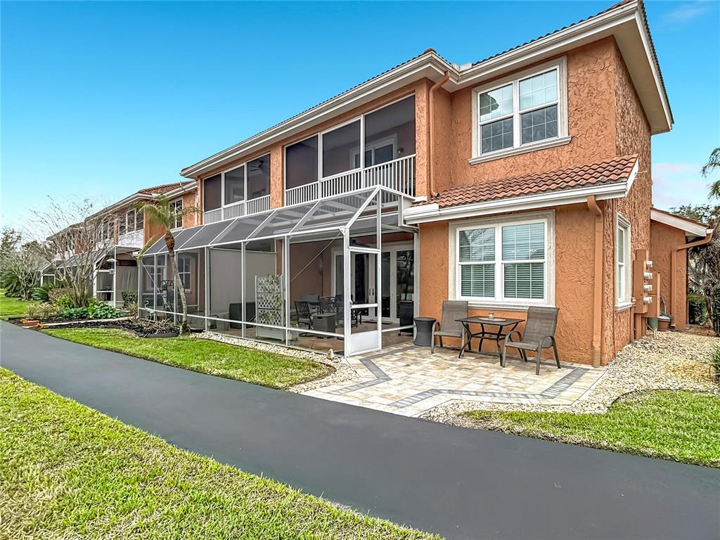 A two-story townhouse with a screened-in patio and a paved outdoor seating area — 6828 SOMBRAS WAY, LAND O LAKES, FL