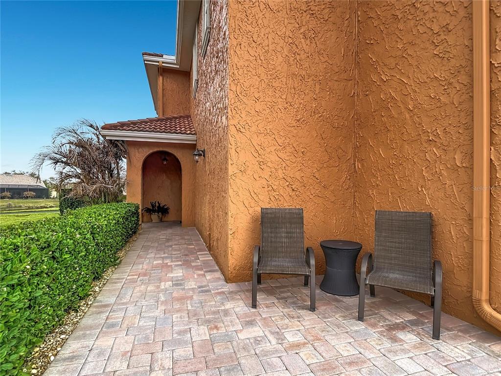 A paved patio area features two chairs and a small table against an orange wall — 6828 SOMBRAS WAY, LAND O LAKES, FL