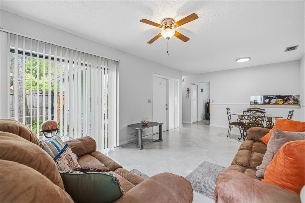 A living room with tile flooring, a ceiling fan, and a sliding glass door — 10307 PENNYTREE PLACE, TAMPA, FL