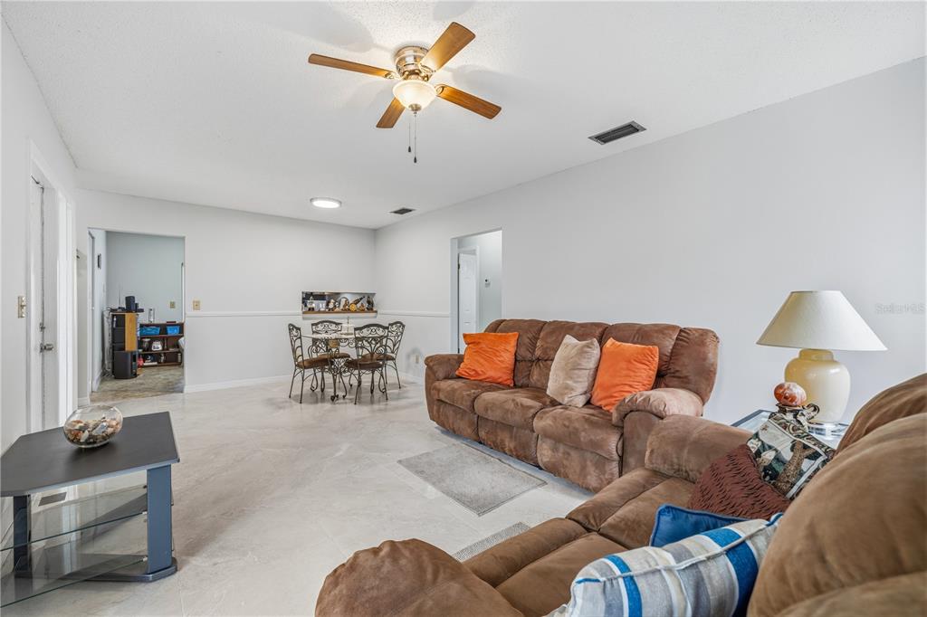 A living room with light tile floors, a brown sectional sofa, and a dining area — 10307 PENNYTREE PLACE, TAMPA, FL