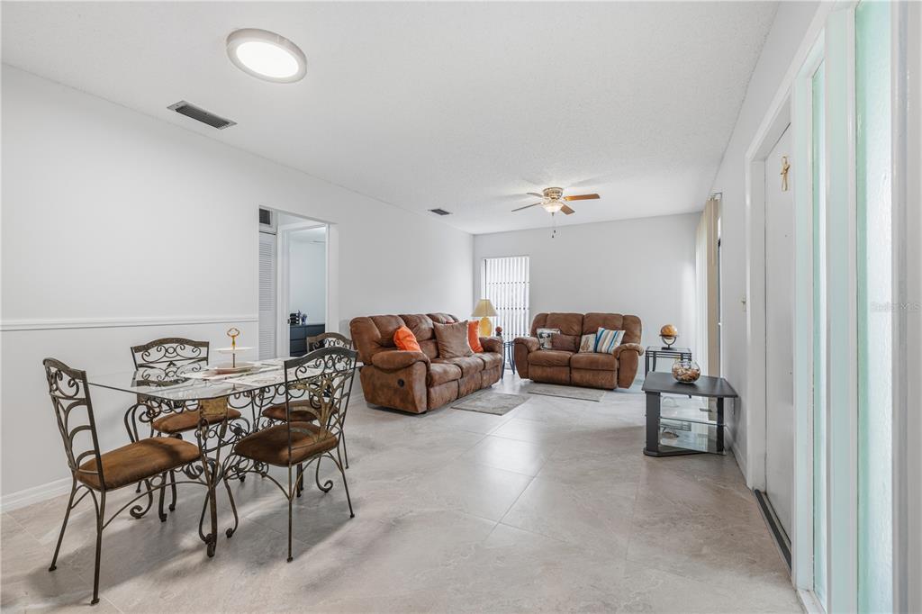 A living and dining room with tile flooring, white walls, and brown leather furniture — 10307 PENNYTREE PLACE, TAMPA, FL