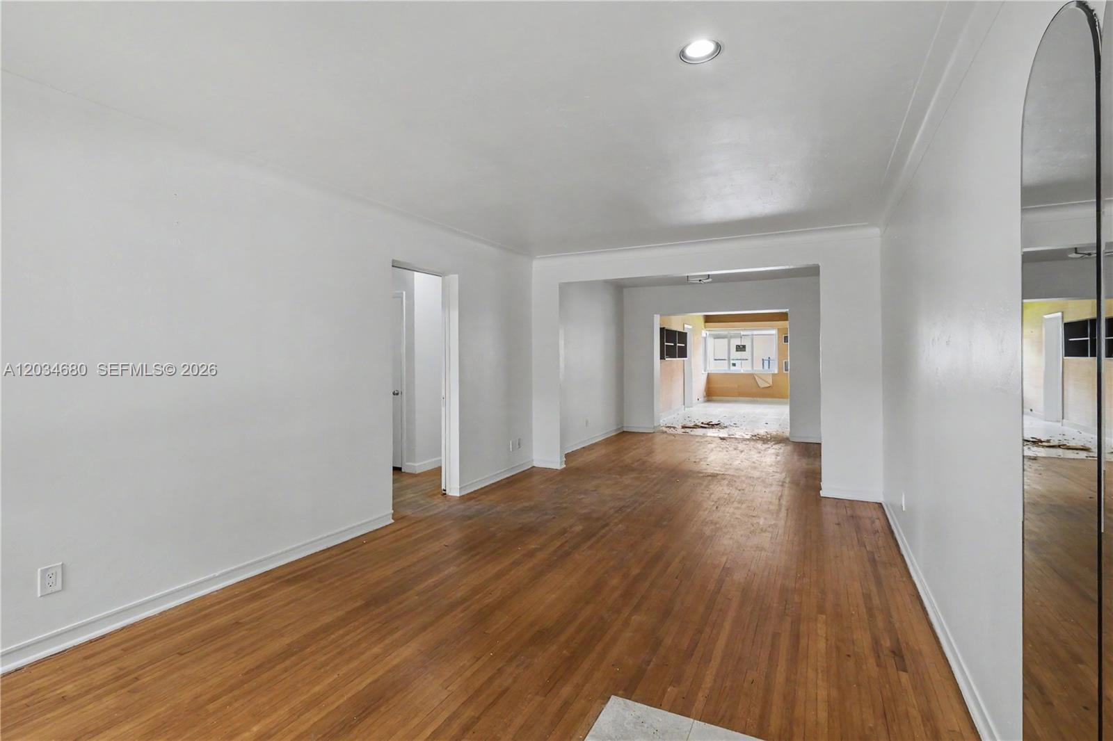 An empty room with hardwood floors, white walls, and a doorway leading to another space — 236 Candia Ave, Coral Gables FL 33134, CORAL GABLES, FL
