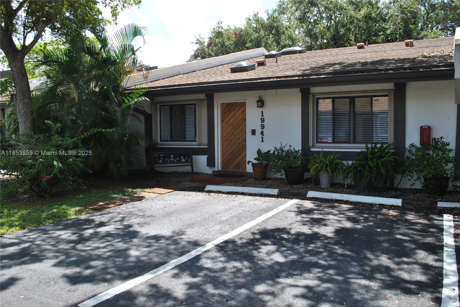 A single-story house with a white stucco facade, dark trim, and a diagonal wood door — 19941 NE 5th Ct # 3M, Miami FL 33179, MIAMI, FL