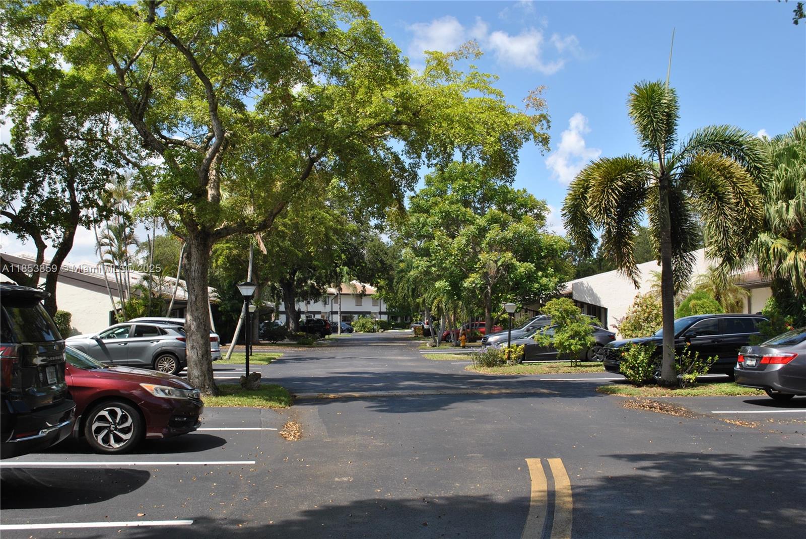 An outdoor parking lot is surrounded by residential buildings, mature trees, and palm trees — 19941 NE 5th Ct # 3M, Miami FL 33179, MIAMI, FL