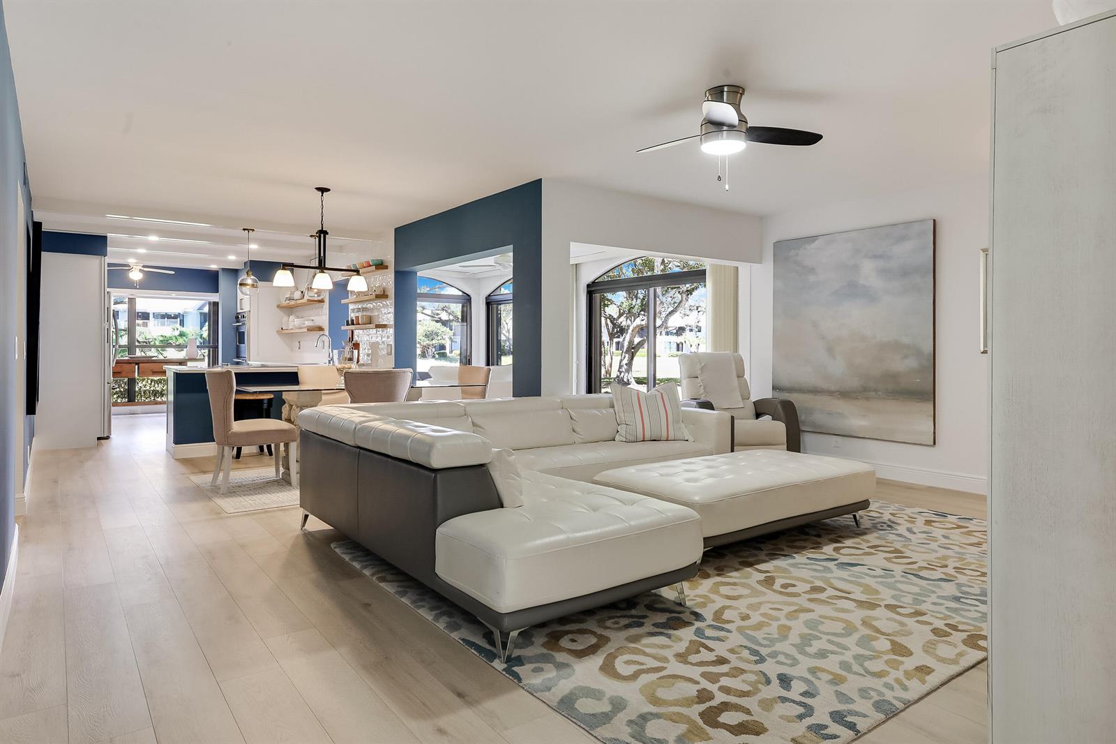 A living room with a white sectional sofa, patterned rug, and an open-concept kitchen area — 16671 Traders Crossing Crossing N # 121, Jupiter FL 33477, JUPITER, FL
