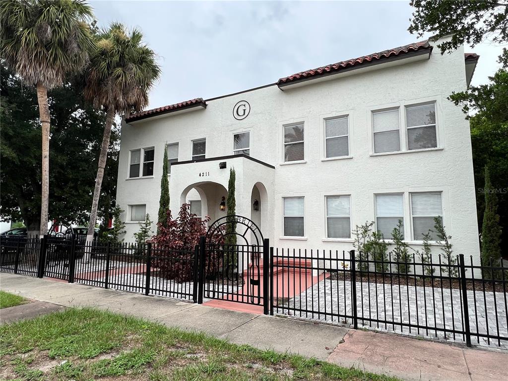 A two-story white stucco building features a central arched entrance and a black metal fence — 4211 W NORTH A STREET UNIT 5, TAMPA, FL