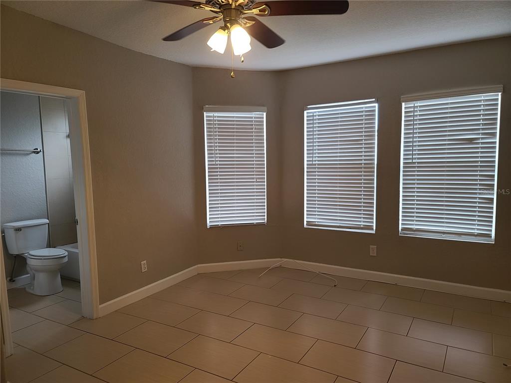 A bedroom with tile flooring, a ceiling fan, three windows, and an attached bathroom — 4211 W NORTH A STREET UNIT 5, TAMPA, FL