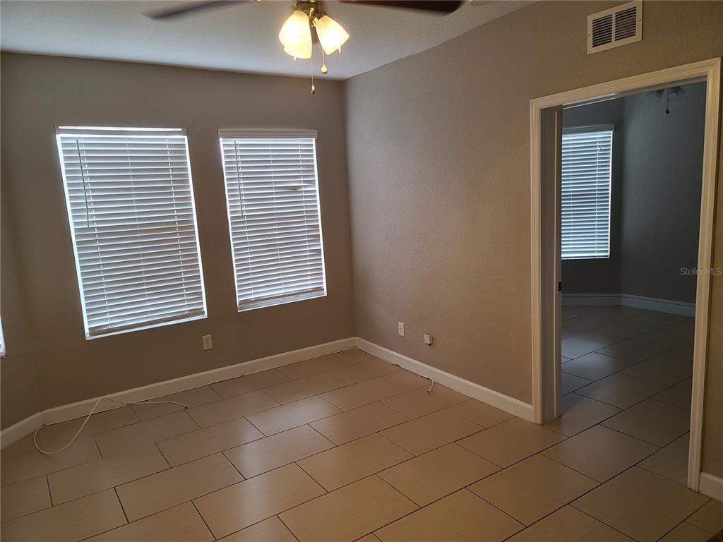 An empty room with beige walls, tile flooring, two windows with blinds, and a doorway — 4211 W NORTH A STREET UNIT 5, TAMPA, FL