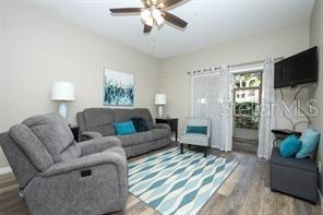 A living room features a gray sofa, a matching armchair, and an open kitchen beyond — 694 SEABROOK COURT UNIT 101, ALTAMONTE SPRINGS, FL