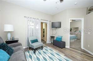 A living room with wood-look flooring, a grey recliner, and an open kitchen in the background — 694 SEABROOK COURT UNIT 101, ALTAMONTE SPRINGS, FL