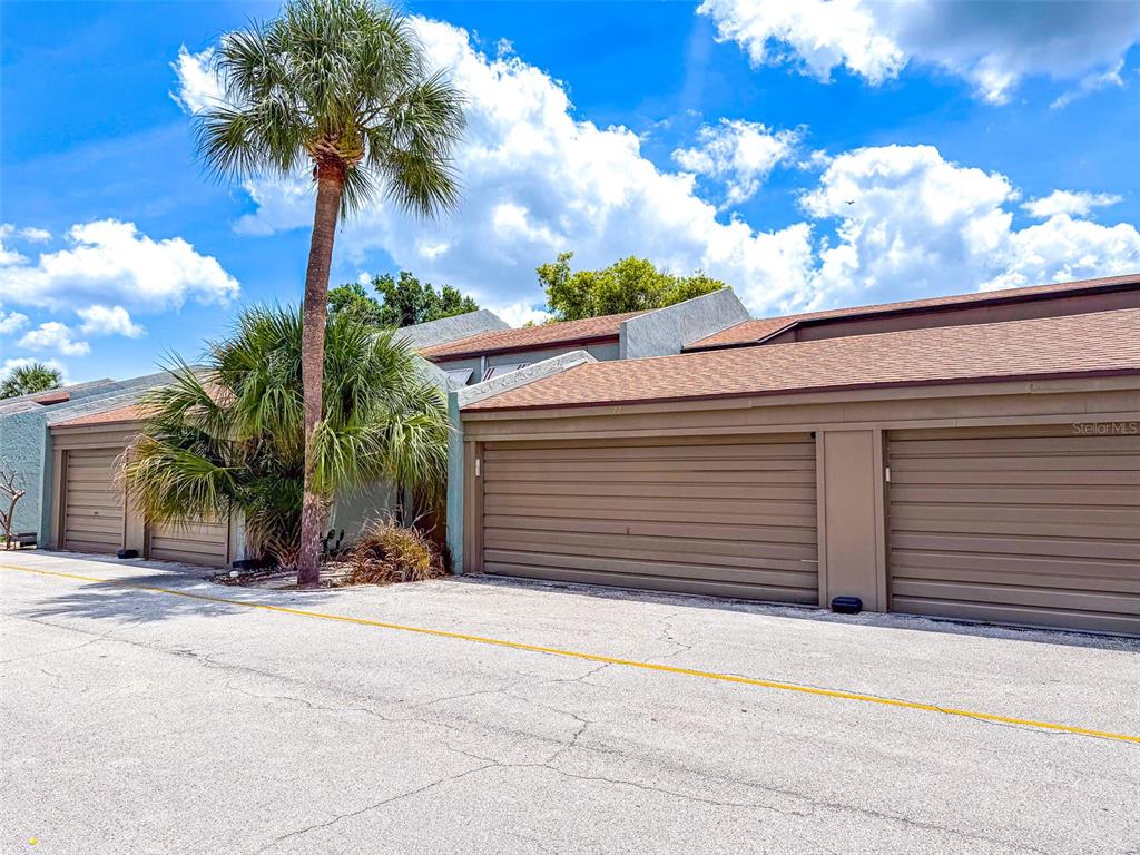 A row of attached garages with brown doors and a palm tree under a blue sky — 2500 21ST STREET NW UNIT 22, WINTER HAVEN, FL