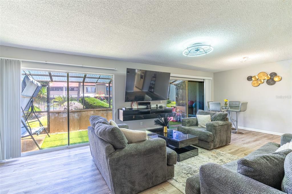 A living room features gray furniture, a wall-mounted television, and sliding glass doors to a patio — 2500 21ST STREET NW UNIT 22, WINTER HAVEN, FL