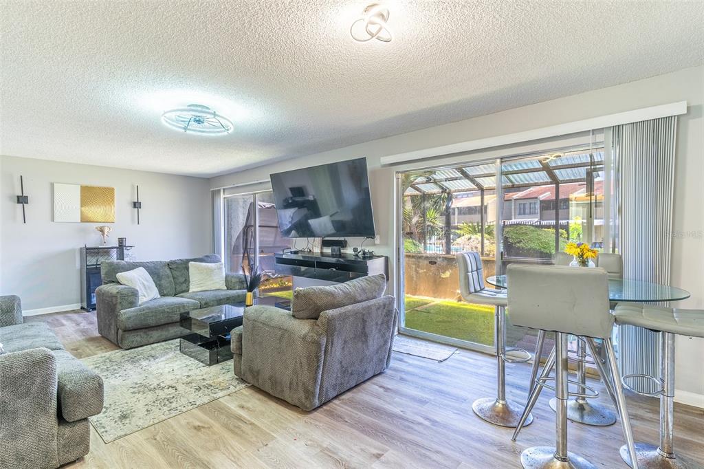 A living room with gray furniture, a wall-mounted television, and a sliding glass door — 2500 21ST STREET NW UNIT 22, WINTER HAVEN, FL