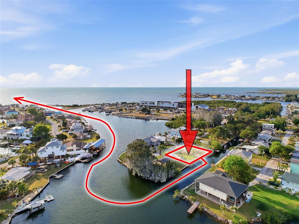 An aerial view shows a vacant waterfront lot highlighted by a red arrow and outline — 14206 HENDRY COURT, HUDSON, FL