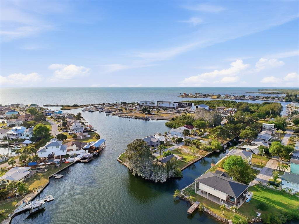 An aerial view shows waterfront homes along a canal leading to a larger bay — 14206 HENDRY COURT, HUDSON, FL
