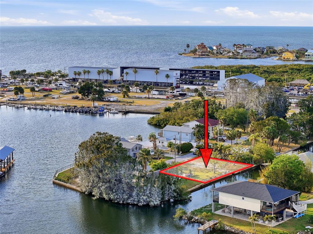 An aerial view shows a vacant waterfront lot outlined in red with a directional arrow — 14206 HENDRY COURT, HUDSON, FL