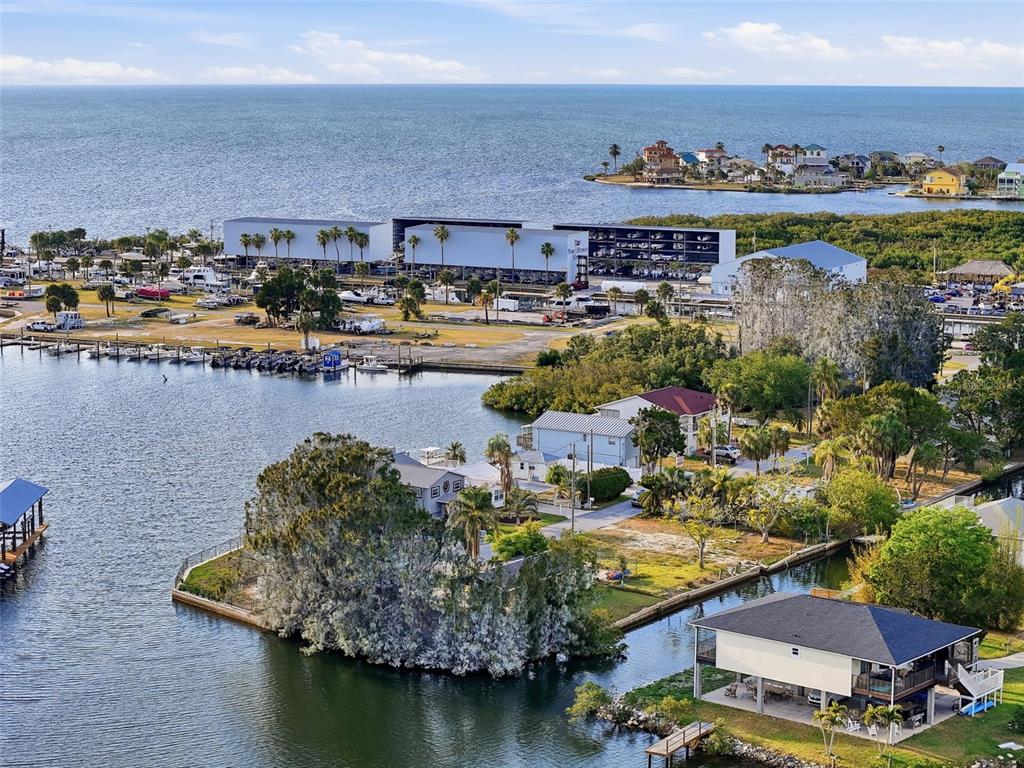 An aerial view shows waterfront homes, a boat storage facility, and a marina on the coast — 14206 HENDRY COURT, HUDSON, FL