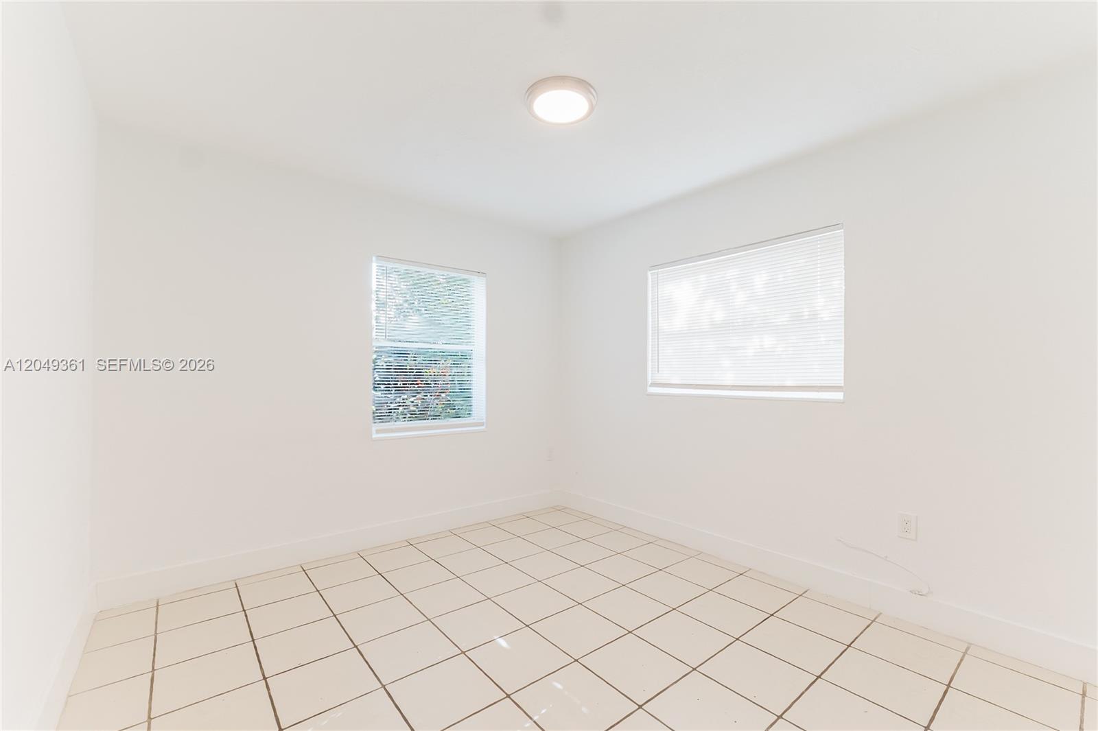 An empty room with white walls, a tiled floor, and two windows with blinds — 6130 Flagler St, Hollywood FL 33023, HOLLYWOOD, FL