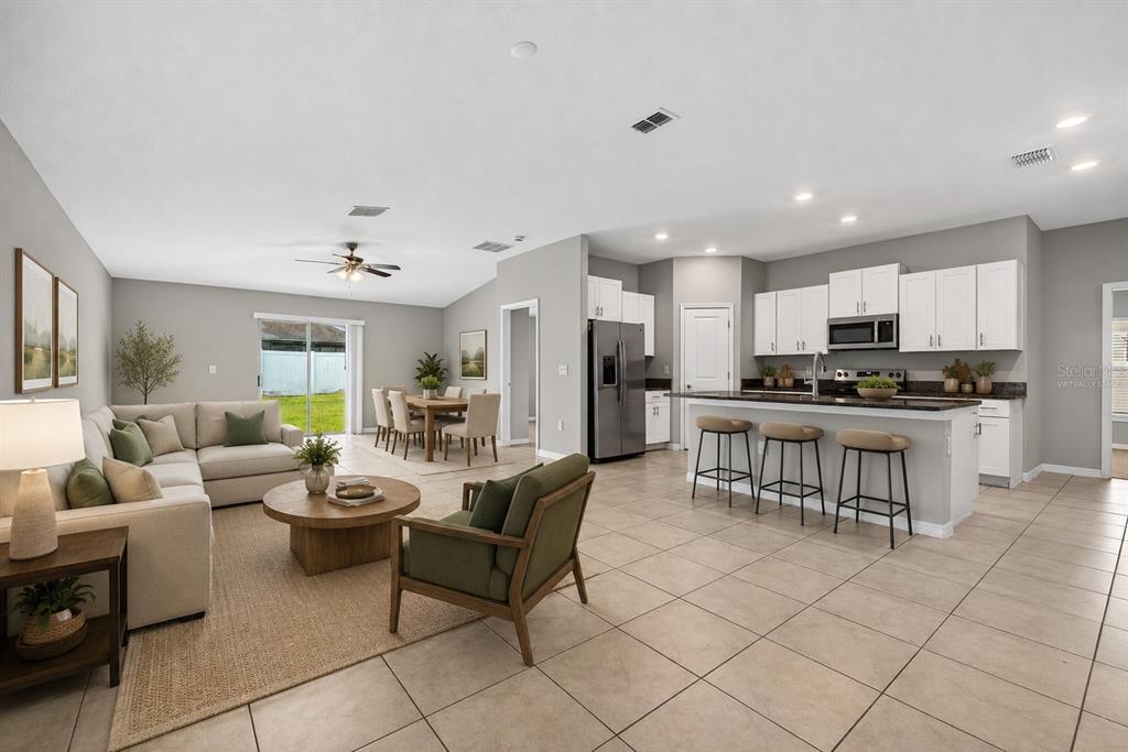 An open-concept living room and kitchen featuring tile flooring, a kitchen island, and neutral walls — 13236 JETER CREEK DRIVE, RIVERVIEW, FL
