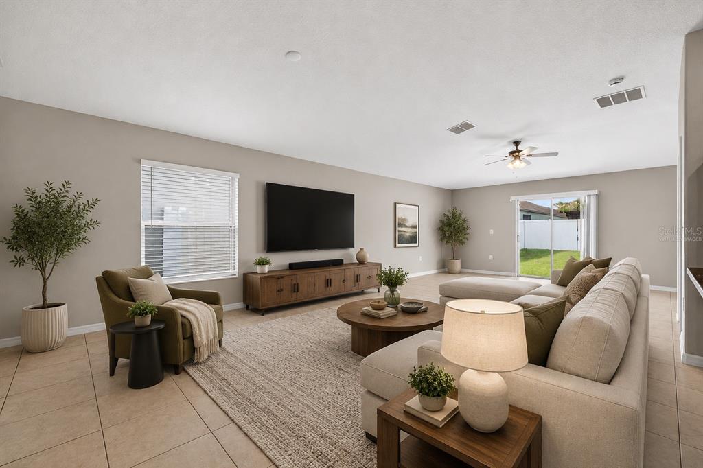 A spacious living room features a large sectional sofa, a television, and tile flooring — 13236 JETER CREEK DRIVE, RIVERVIEW, FL