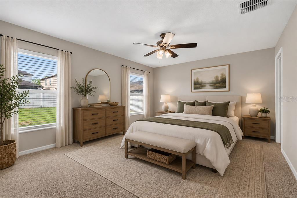 A bedroom features a bed with neutral bedding, a wooden dresser, and two windows — 13236 JETER CREEK DRIVE, RIVERVIEW, FL