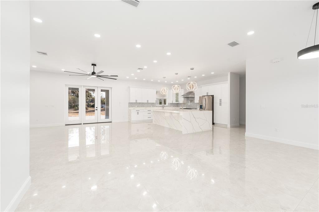 A bright, open-concept kitchen and living area with white cabinetry, marble island, and tile floors — 11920 SE 8TH AVENUE, OCALA, FL