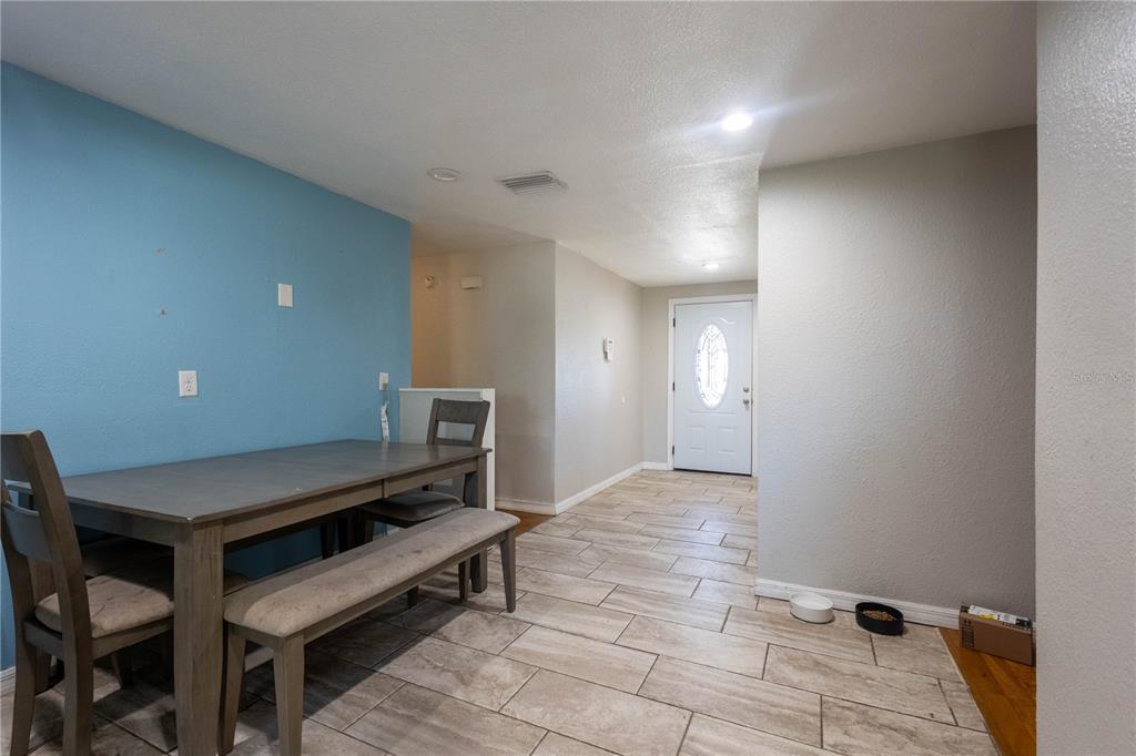 A dining area with a blue accent wall, wooden table, and tiled flooring near an entryway — 724 TRADEWINDS DRIVE, BRANDON, FL