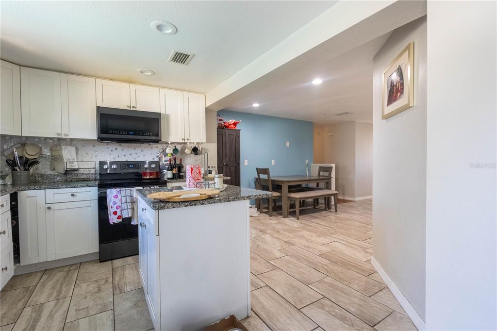 A kitchen with white cabinets and granite countertops opens into a dining area with blue walls — 724 TRADEWINDS DRIVE, BRANDON, FL
