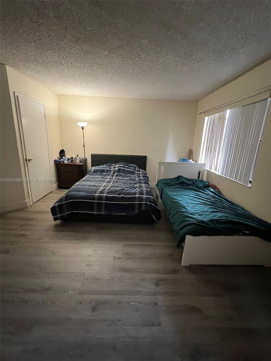 A bedroom features wood-look flooring, a double bed, a single bed, and vertical window blinds — 9429 Fontainebleau Blvd # 33, Miami FL 33172, MIAMI, FL