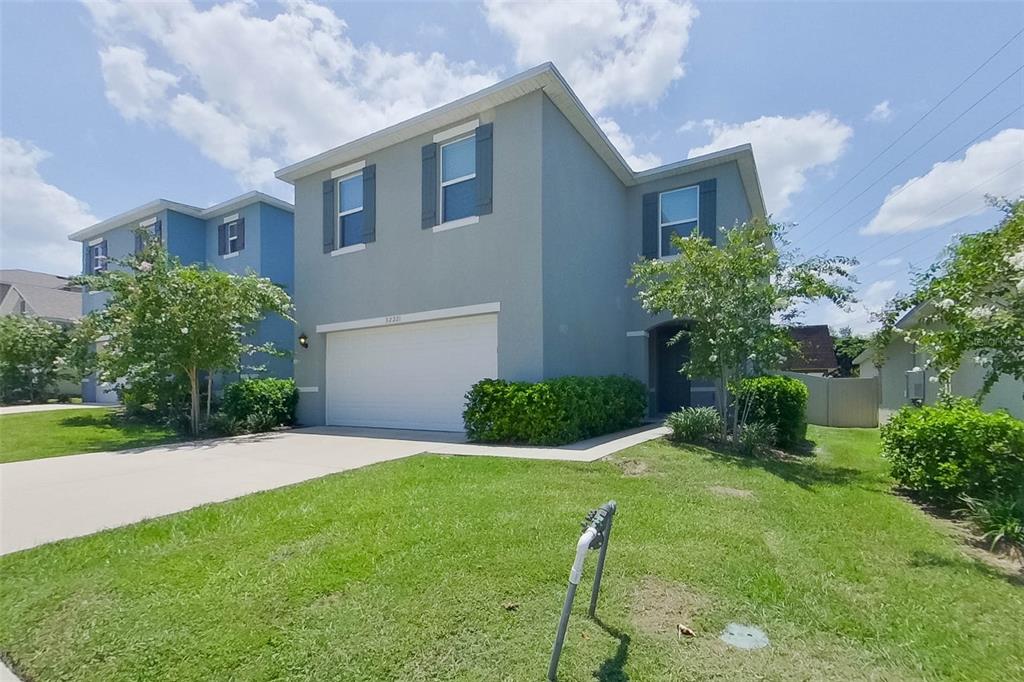 A two-story gray house with a two-car garage and a front lawn under a sky — 32221 EDSON AVE, LEESBURG, FL