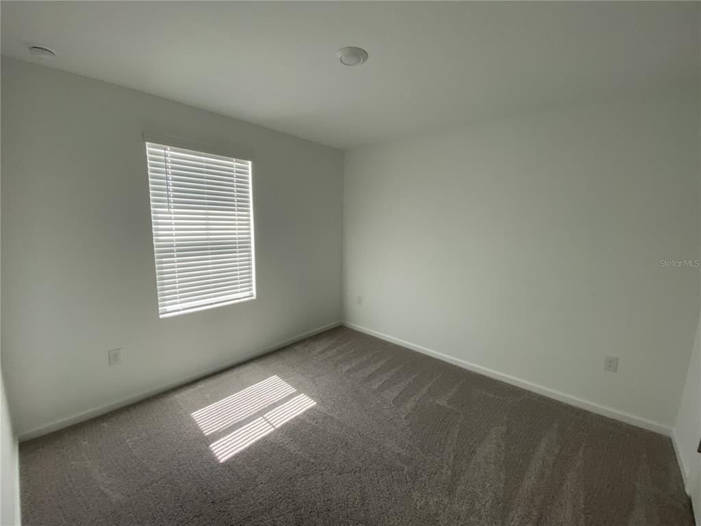 An empty bedroom features white walls, gray carpeting, a window with blinds, and recessed lighting — 3451 VESARA DRIVE, DAVENPORT, FL
