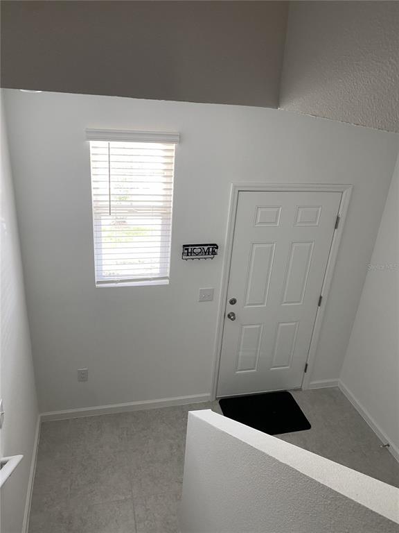 An entryway features a white door, a window with blinds, and light-colored tile flooring — 3451 VESARA DRIVE, DAVENPORT, FL