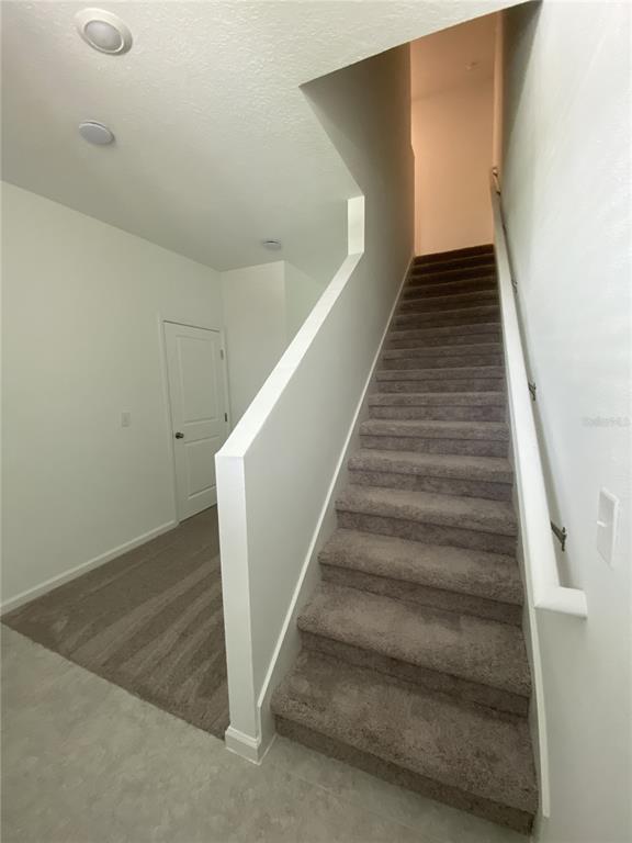 A carpeted staircase leads to an upper level next to a closed white interior door — 3451 VESARA DRIVE, DAVENPORT, FL