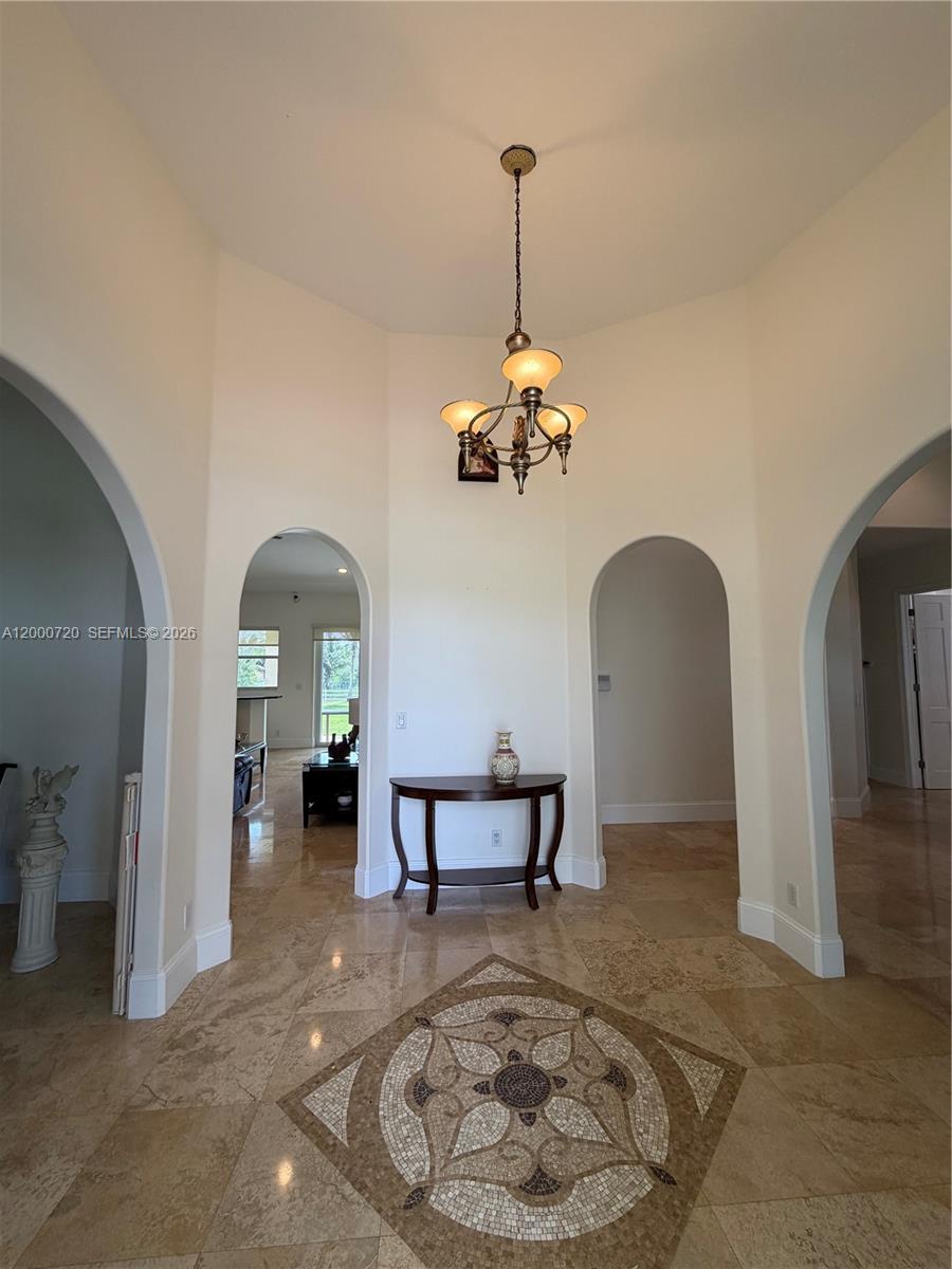 A foyer features a mosaic floor medallion, arched doorways, and a hanging chandelier — 4810 SW 198th Ter, Southwest Ranches FL 33332, SOUTHWEST RANCHES, FL