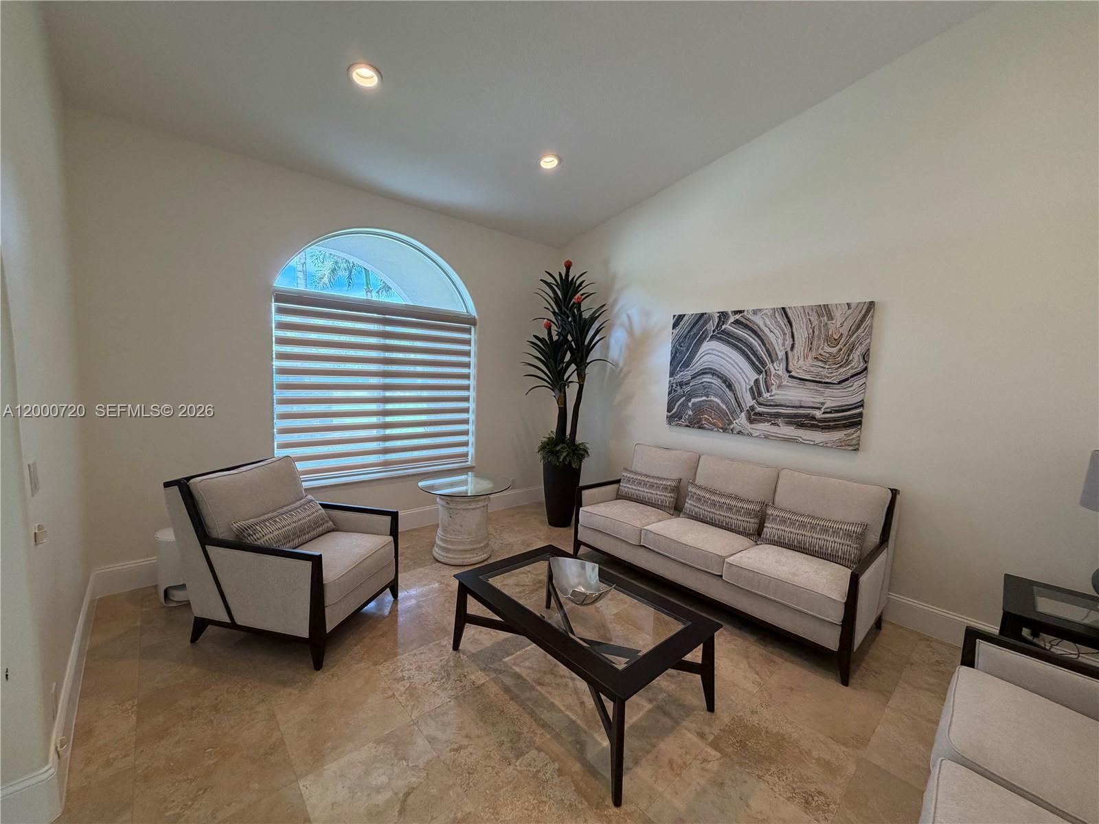 A living room features a sofa, armchair, coffee table, and arched window with blinds — 4810 SW 198th Ter, Southwest Ranches FL 33332, SOUTHWEST RANCHES, FL