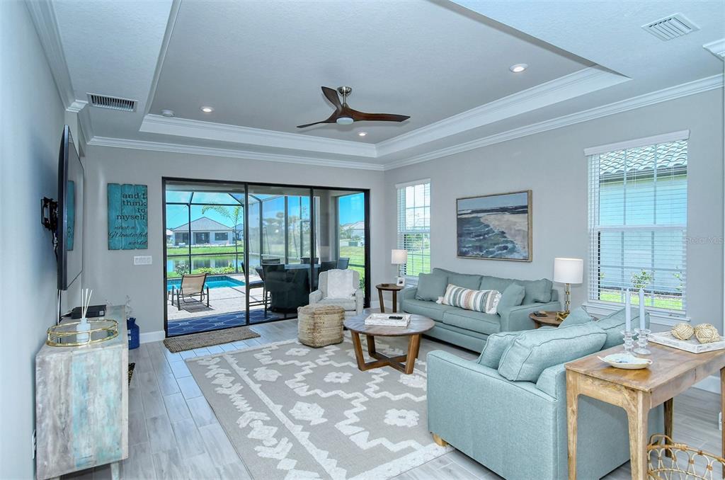 A living room with light blue sofas, a patterned rug, and sliding doors to a pool — 4708 MOTTA COURT, BRADENTON, FL