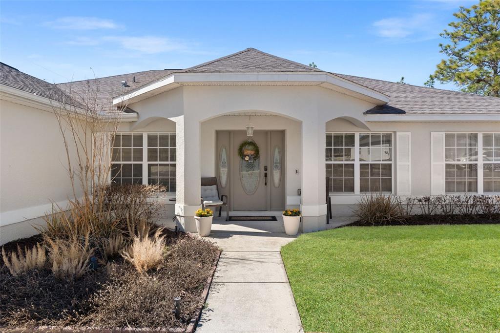 The exterior of a single-story house features a covered entryway with a beige front door — 15335 FLEETWOOD ROAD, WEEKI WACHEE, FL
