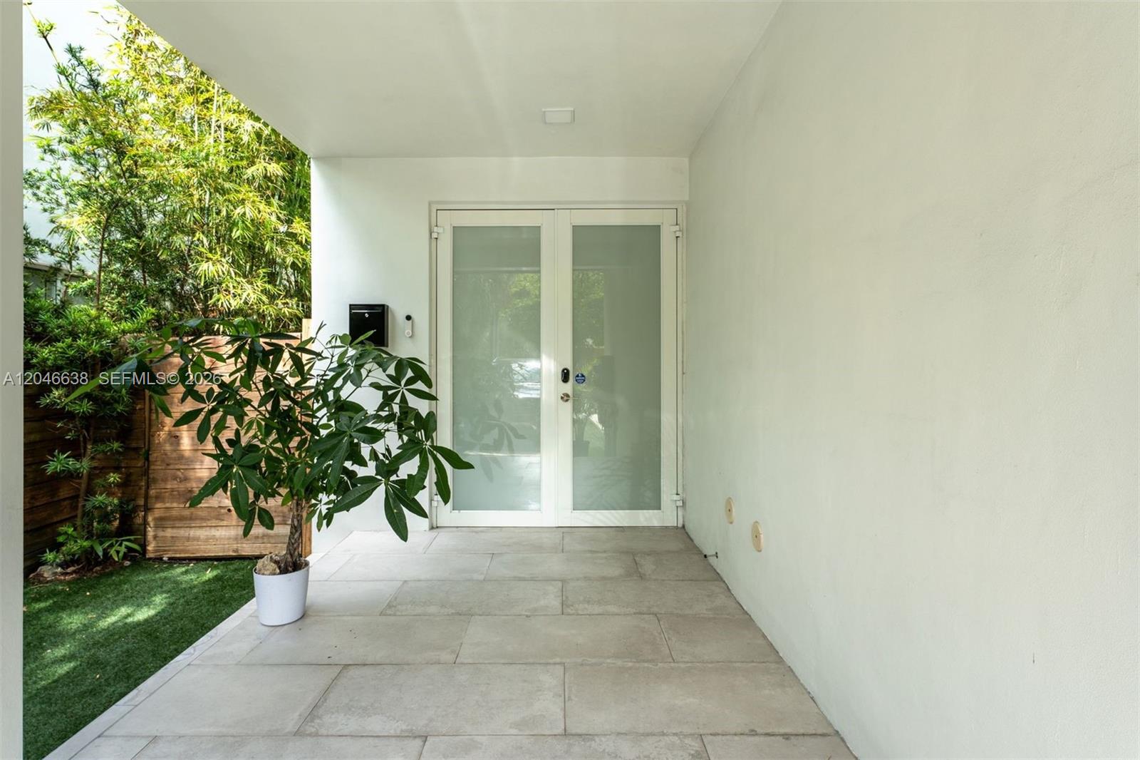 A covered patio features light-colored tile flooring, a potted plant, and white double glass doors — 2908 Virginia St # 2908, Miami FL 33133, MIAMI, FL