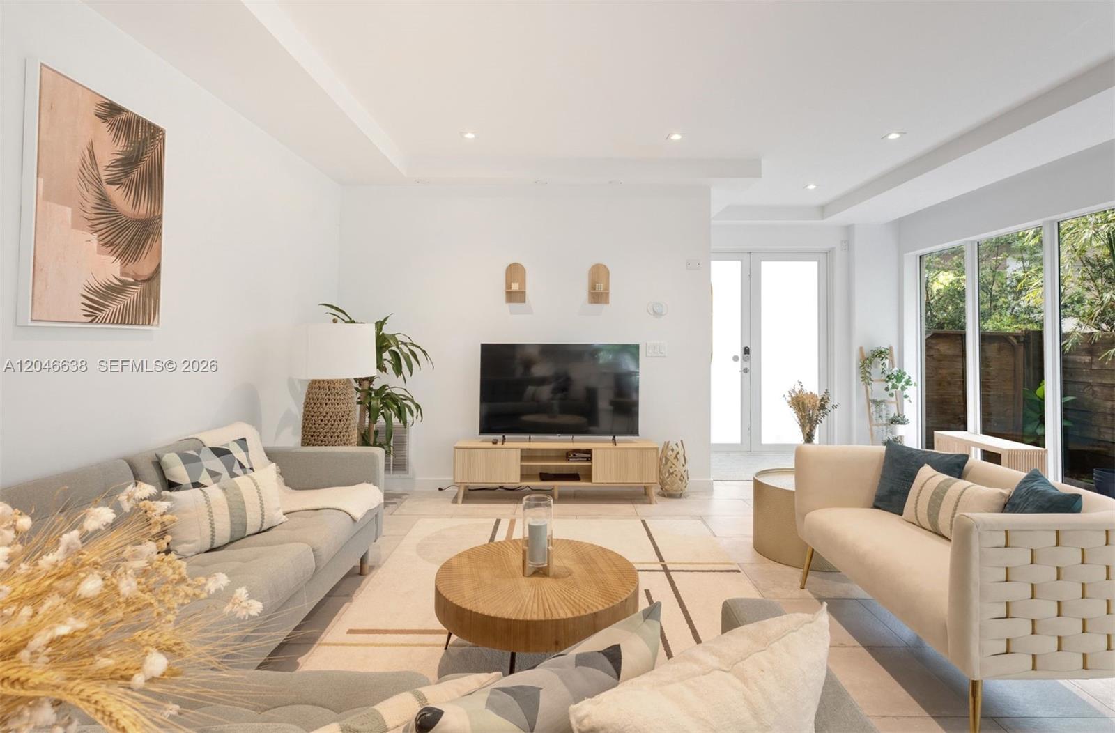 A bright living room features a television, two sofas, a round coffee table, and tile flooring — 2908 Virginia St # 2908, Miami FL 33133, MIAMI, FL