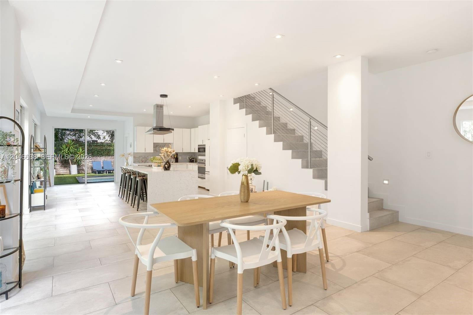 A modern open-plan dining area features a wooden table, white chairs, and a kitchen — 2908 Virginia St # 2908, Miami FL 33133, MIAMI, FL