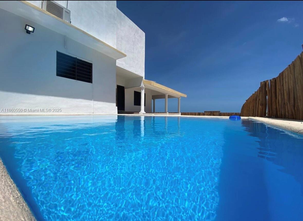 A swimming pool sits in front of a white building with a wooden fence — Calle 18 y 2 Telchak Puerto, Mx, Mx