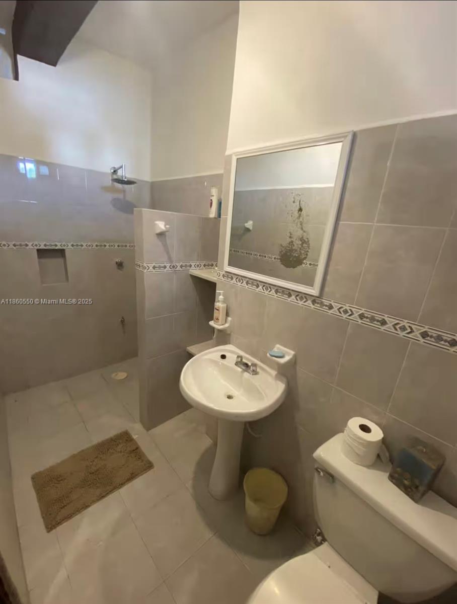 A bathroom features a pedestal sink, a toilet, and a walk-in shower with tiled walls — Calle 18 y 2 Telchak Puerto, Mx, Mx