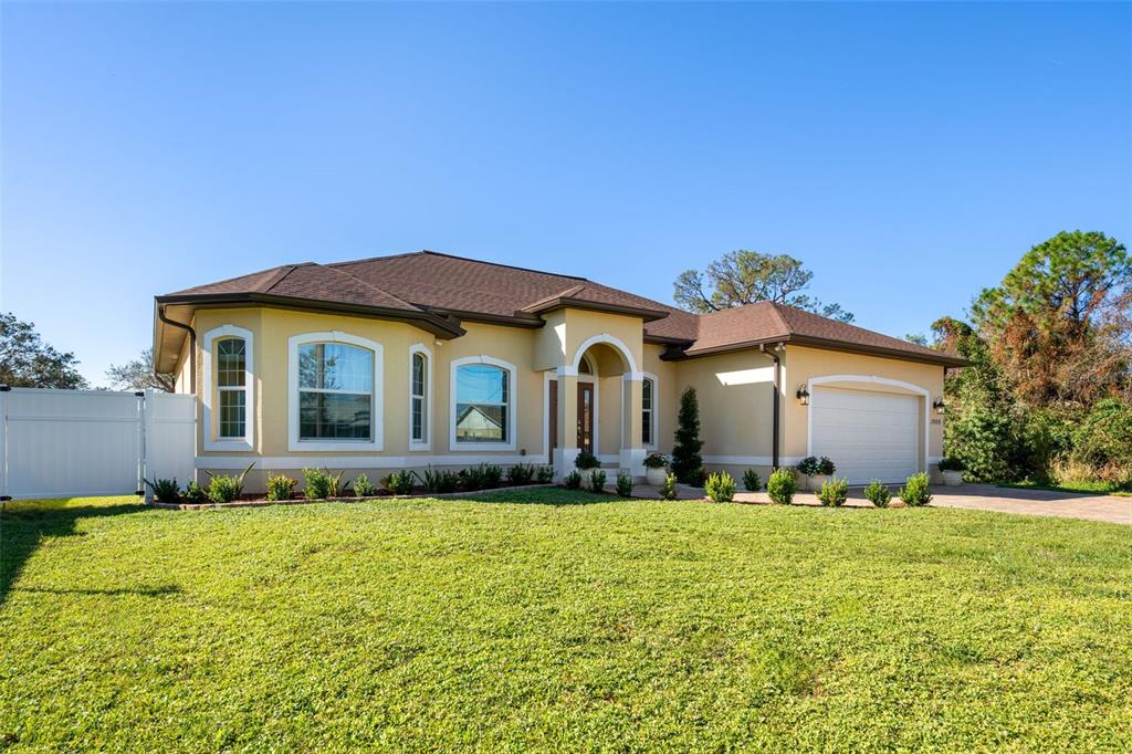 A single-story house with a beige stucco exterior, brown roof, and an attached two-car garage — 1900 COLLEEN STREET, SARASOTA, FL