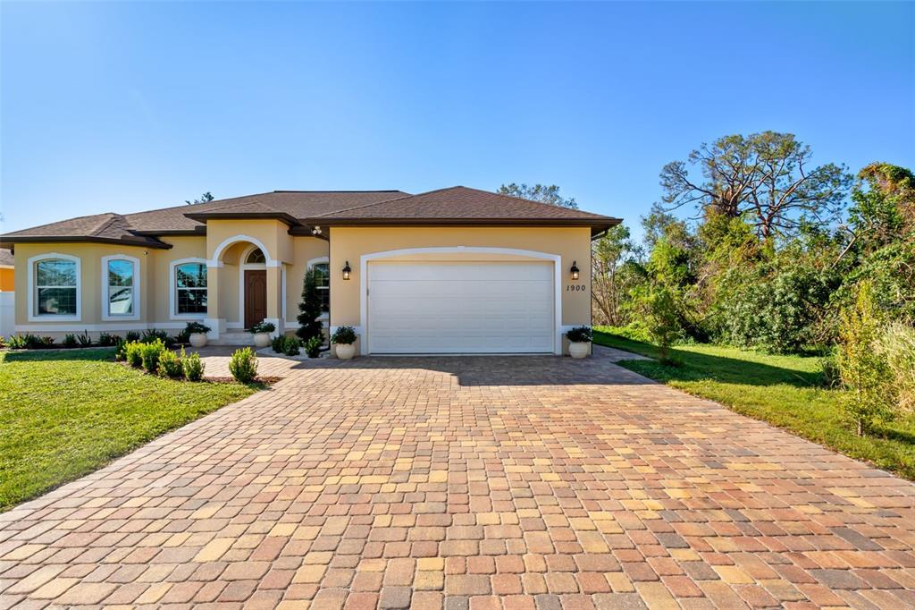 A single-story house with a beige stucco exterior, a brown roof, and a paver driveway — 1900 COLLEEN STREET, SARASOTA, FL