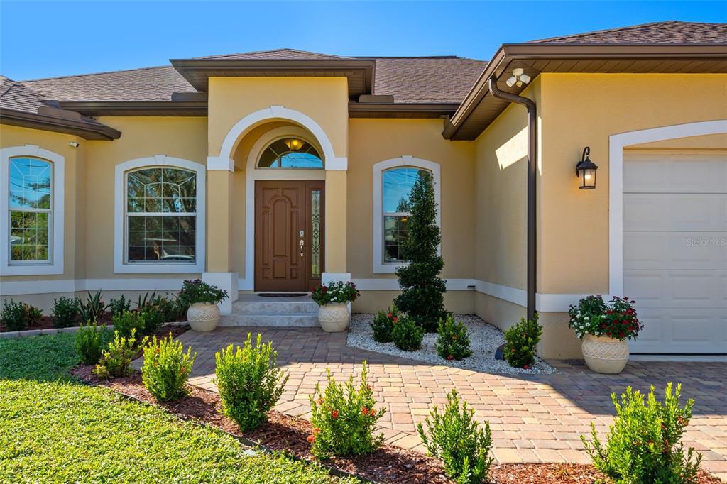 The exterior of a single-story house features a paved walkway, a brown door, and landscaping — 1900 COLLEEN STREET, SARASOTA, FL