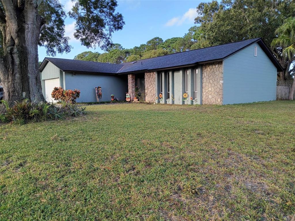 A single-story house with blue siding, stone accents, and a large tree in the front yard — 10700 GARDENWOOD ROAD, ORLANDO, FL